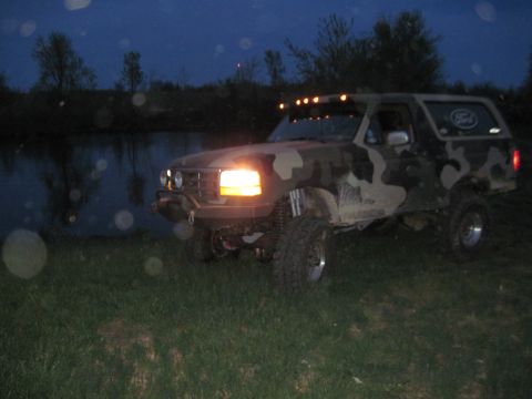 1995 Ford Bronco - This lifted Ford Bronco is parked near a body of water as daylight fades.