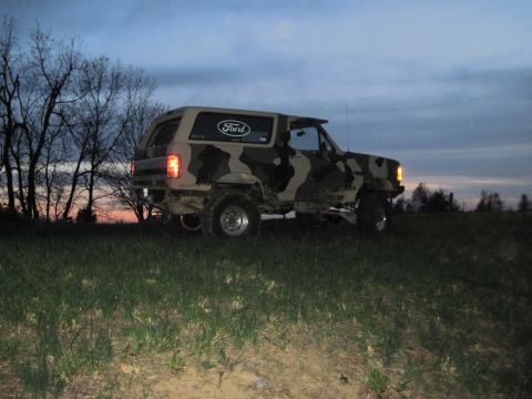 1995 Ford Bronco - This 1995 Ford Bronco, sporting a camouflage paint job, is seen parked on a grassy incline during twilight.