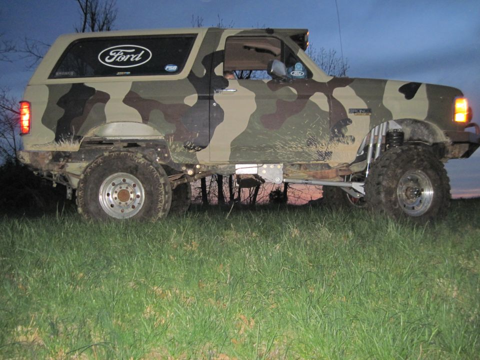 1995 Ford Bronco with camouflage paint, lifted suspension, and off-road tires parked in grass