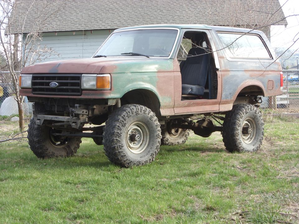 1988 Ford Bronco with lifted suspension, missing doors, and custom paint
