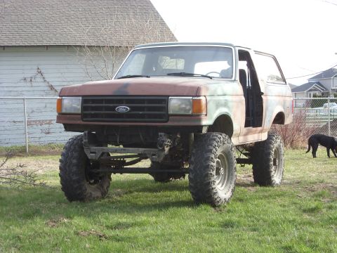 1988 Ford Bronco - This heavily modified Ford Bronco features a significant lift and oversized tires, with its doors removed.