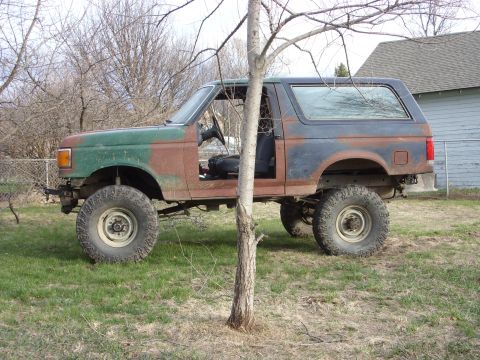 1988 Ford Bronco - This 1988 Ford Bronco shows significant rust and modifications, including a lifted suspension and large off-road tires.