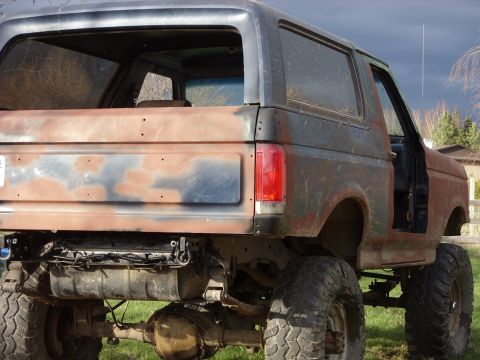1988 Ford Bronco - This heavily modified Ford Bronco shows significant rust and body damage, with its rear section visible.