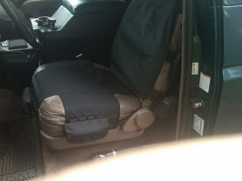 1993 Ford Bronco - The interior of a vehicle, showing the driver's seat covered in black fabric, with the center console visible.