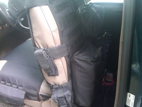1993 Ford Bronco - Vehicle interior shows a tactical seat cover with multiple pouches and a holster attached.