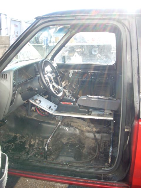 1992 Ford Ranger - The interior of a truck shows an aftermarket steering wheel and a removed door panel, suggesting modifications or repairs.