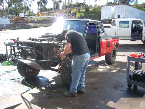 1992 Ford Ranger - Mechanic works on the engine of a 1992 Ford Ranger with a custom front bumper.