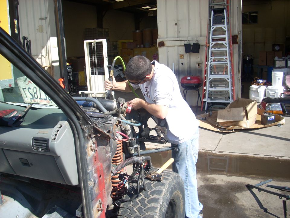 Man working on engine of a disassembled vehicle, inside a garage