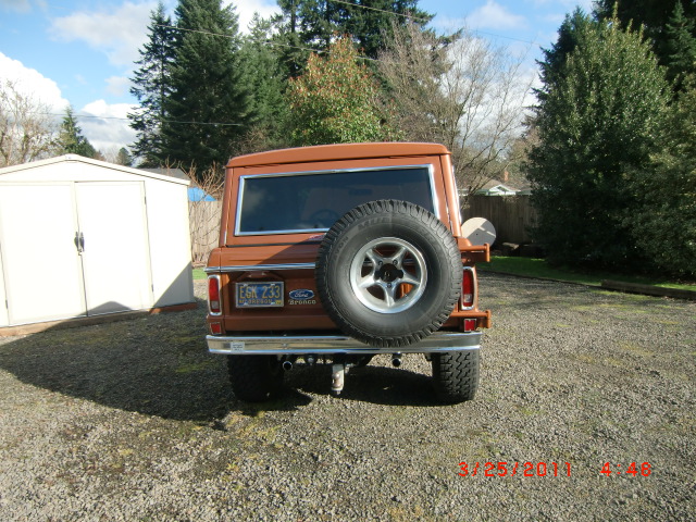 Rear view of a brown 1973 Ford Bronco with a spare tire mounted on the back. License plate is visible