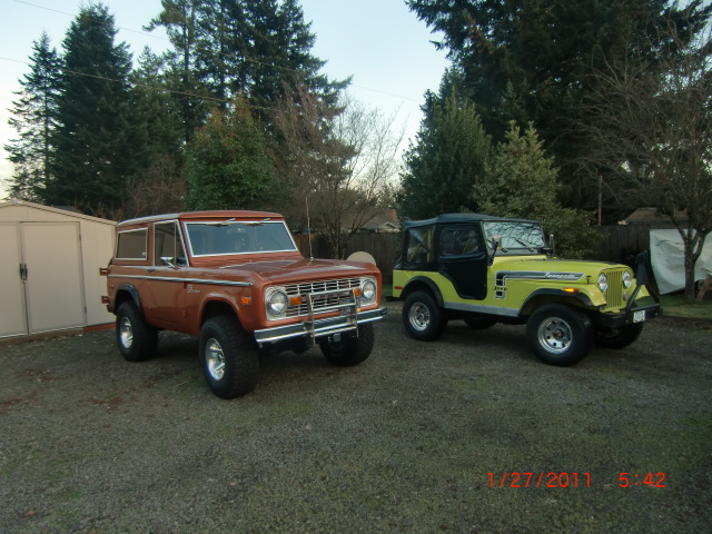 Orange 1973 Ford Bronco parked next to a yellow Jeep CJ