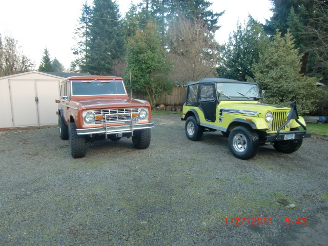 1973 Ford Bronco parked next to a yellow Jeep CJ-5