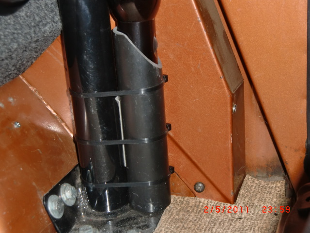 Vehicle interior with black tubes secured by zip ties against orange paneling and carpet