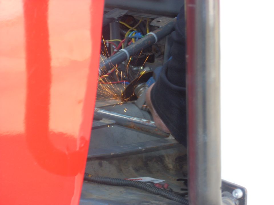 Grinding metal sparks fly inside a vehicle's interior, near wiring and roll cage tubing