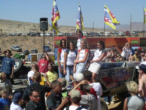 1979 Ford Bronco - A crowd gathers around a custom off-road vehicle at an outdoor event with flags and banners in the background.