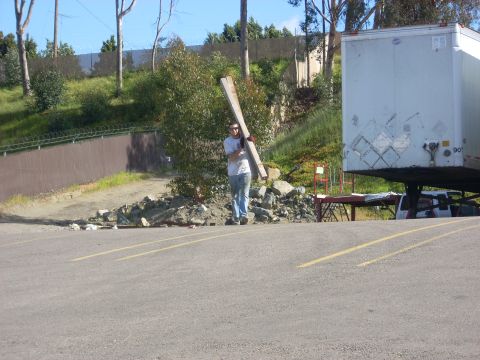 1992 Ford Ranger - A man carries lumber across a parking lot, with a semi-trailer visible to the right.
