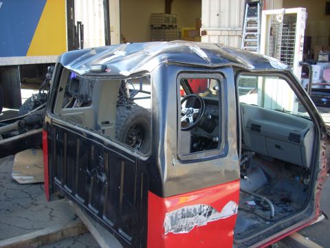 1992 Ford Ranger - The cab of a pickup truck is shown with a severely damaged roof and exposed interior, sitting on wooden blocks.