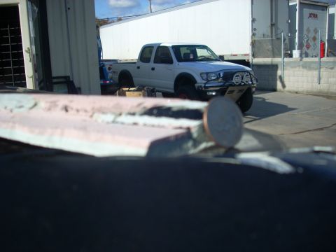 1992 Ford Ranger - A white Toyota Tacoma pickup truck is parked in front of a large white trailer and a loading dock.