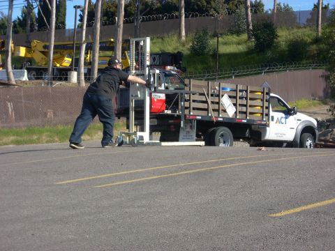 1992 Ford Ranger - Forklift being loaded onto a flatbed truck. Another vehicle is parked in the background.