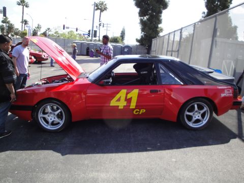 1993 Ford Taurus - A red race car with yellow numbers and racing modifications is displayed with its hood open.