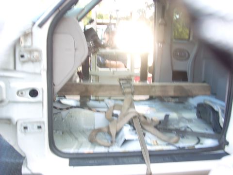 1992 Ford Ranger - The interior of a vehicle is shown with the seats removed, revealing the floor and wiring, with a wooden beam secured by straps.