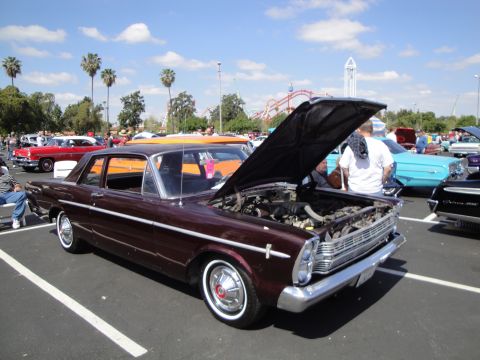1993 Ford Taurus - A maroon 1965 Ford sedan is displayed with its hood open at a car show.