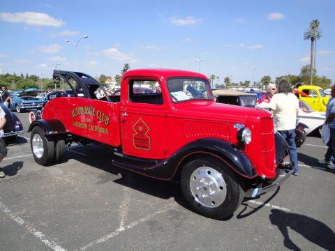1993 Ford Taurus - A vintage red tow truck is parked at an outdoor event with other vehicles visible.