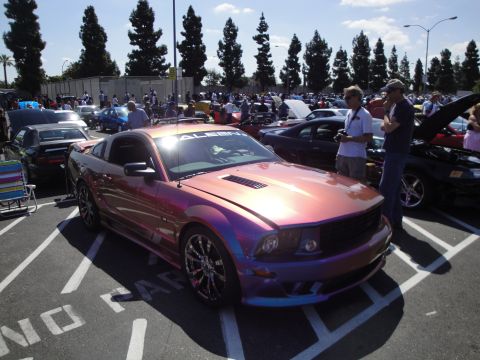 1993 Ford Taurus - A Ford Mustang with custom iridescent paint is displayed at a car show.