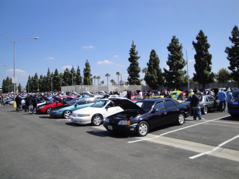1993 Ford Taurus - A car show or gathering with multiple vehicles displayed in a parking lot.