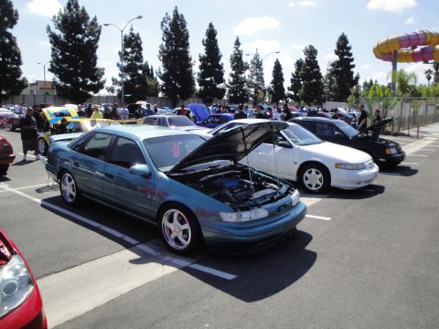 1993 Ford Taurus - A teal 1993 Ford Taurus sedan is displayed with its hood open at an outdoor event.