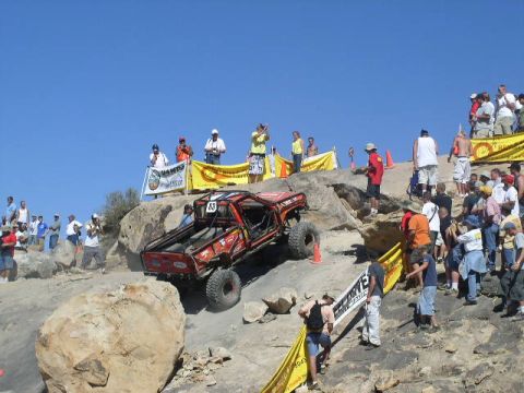 1979 Ford Bronco - Spectators watch an off-road vehicle navigate a challenging rocky terrain during an event.