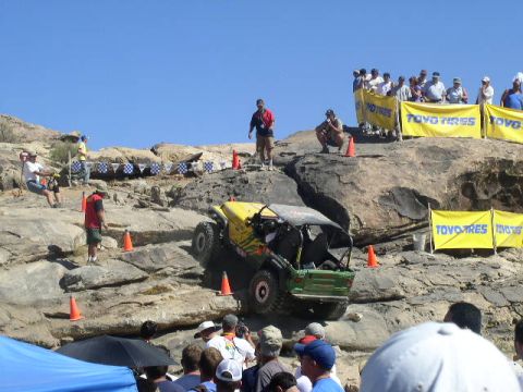 1979 Ford Bronco - An off-road vehicle navigates a rocky course during a competition, with spectators gathered on the hillside.