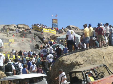 1979 Ford Bronco - Spectators gather to watch off-road vehicles compete on a challenging rocky course under a clear blue sky.