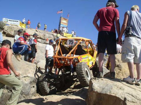 1979 Ford Bronco - A buggy navigates a tough off-road course, with spectators gathered on the rocks above.