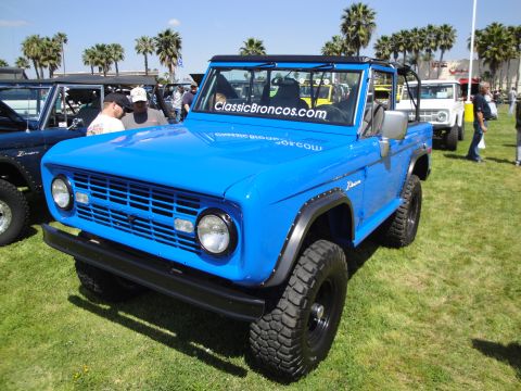 1993 Ford Taurus - A bright blue first-gen Ford Bronco is displayed at an outdoor event with other vehicles present.