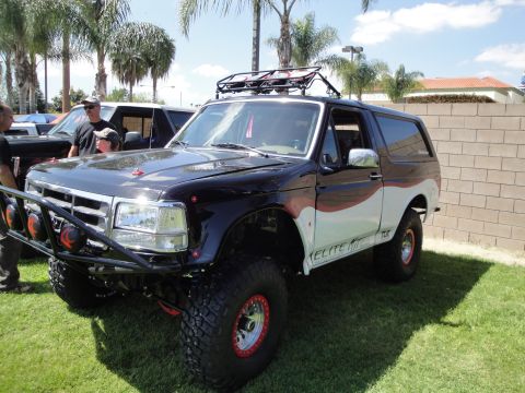 1993 Ford Taurus - A modified 1996 Ford Bronco is parked on grass with another vehicle behind it.