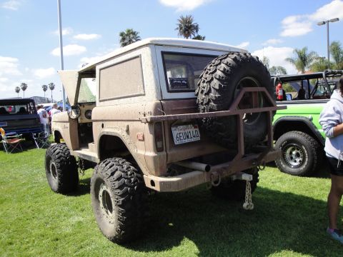 1993 Ford Taurus - A dusty brown Ford Bronco is parked on grass next to a green Jeep.
