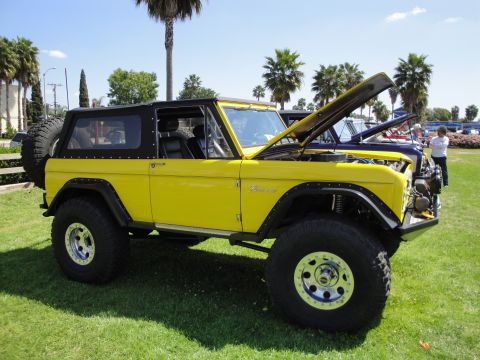 1993 Ford Taurus - Modified 1975 Ford Bronco on display with its hood up, parked next to other vehicles.