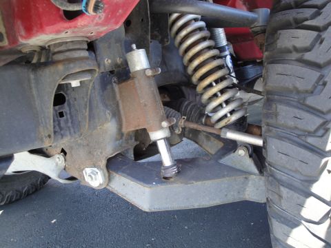 1993 Ford Taurus - Close-up view of the front suspension system of a red vehicle, showing the coilover shock absorber and part of the tire.
