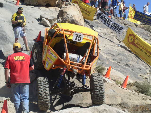 Yellow off-road buggy with number 75 on a rocky incline
