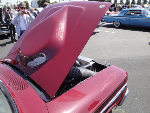 1993 Ford Taurus - A red car with its hood open reveals a 427 cubic inch decal and flame pinstriping on the fender, with another blue car visible in the backg…
