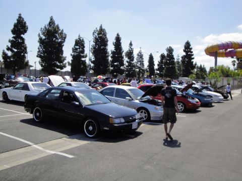 1993 Ford Taurus - A black 1993 Ford Taurus is parked at an outdoor car show with many other vehicles.