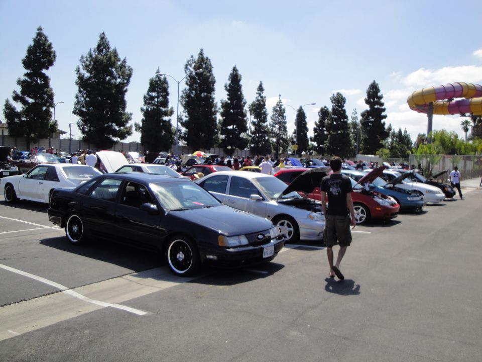 Black 1993 Ford Taurus parked in lot with other cars, person walking away