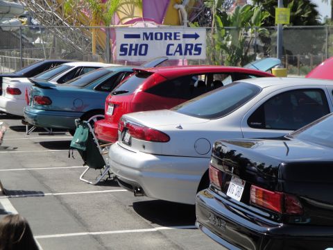 1993 Ford Taurus - A row of cars are parked in a lot, with a sign indicating more cars are available.