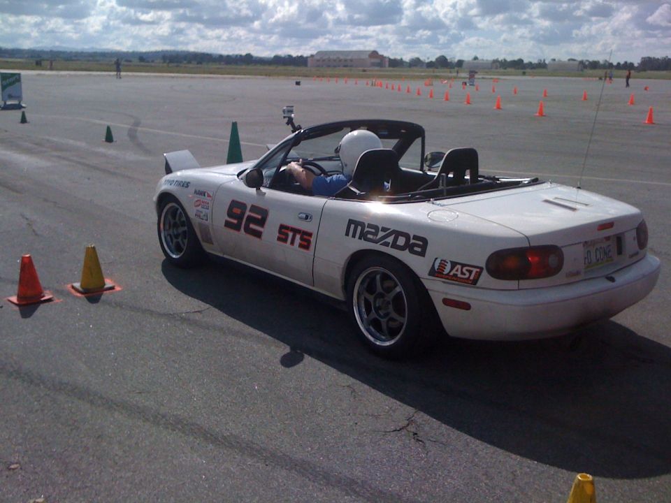 White 1991 Mazda Miata convertible with racing decals on a track
