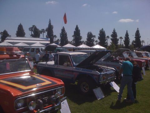 1996 Ford C-350 (Centurion Conversions) - A line of vehicles are displayed outdoors under a sunny sky with tents in the background.
