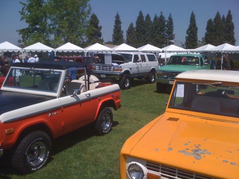 1996 Ford C-350 (Centurion Conversions) - Several classic Ford vehicles are displayed outdoors under white tents on a sunny day.