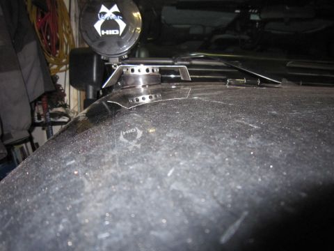 2008 Jeep Wrangler - Close-up of a black Jeep Wrangler hood, showing a custom light mount and an HID light, with dust visible on the surface.
