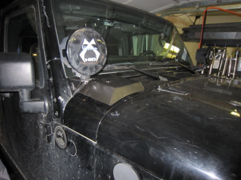2008 Jeep Wrangler - Cowl area of a black Jeep Wrangler JK in a garage, with a round Vision X HID off-road light mounted at the windshield hinge and a dark meta…