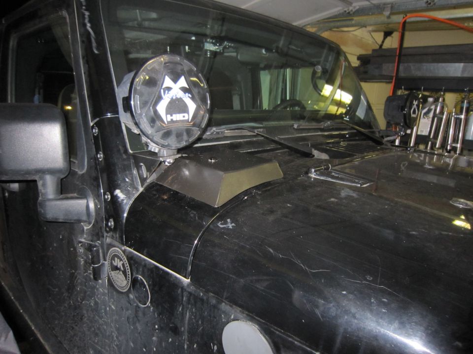 Black Jeep Wrangler JK cowl with Vision X HID light and fender-mounted metal vent in a garage