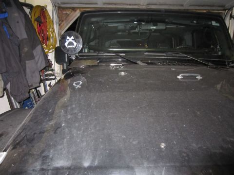 2008 Jeep Wrangler - A black Jeep Wrangler is parked in a garage, showing its hood and windshield with an auxiliary light on the fender.